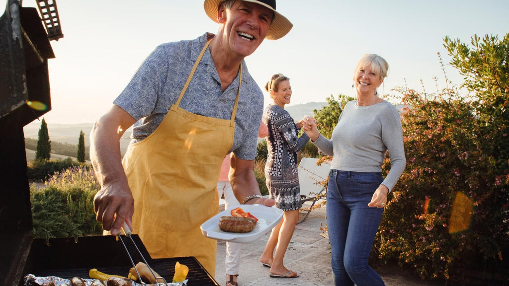 happy famil bbq man standing by bbq with hat on and bbq tongs