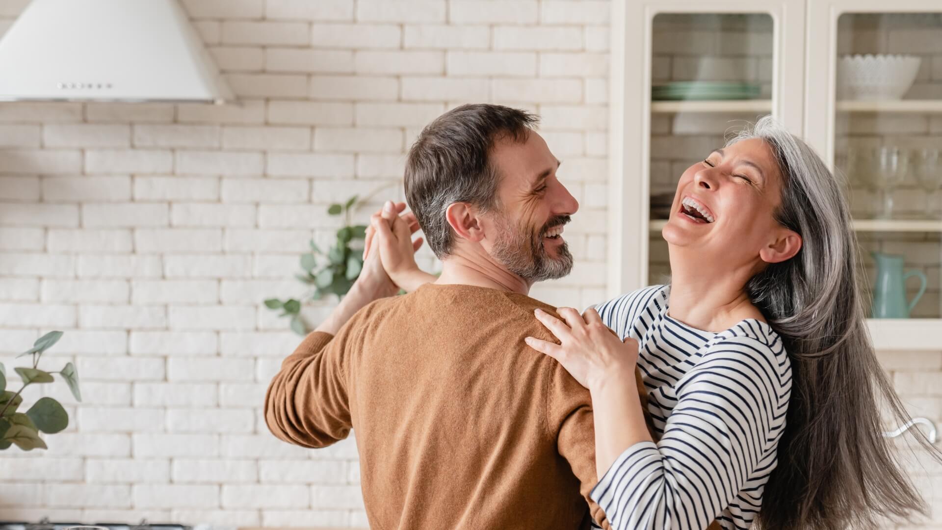 happy midlife couple in kitchen dancing