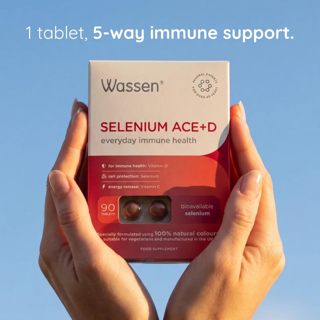A person's hands holding a box of Wassen Selenium ACE+D tablets against a clear blue sky. White text at the top reads '1 tablet, 5-way immune support.
