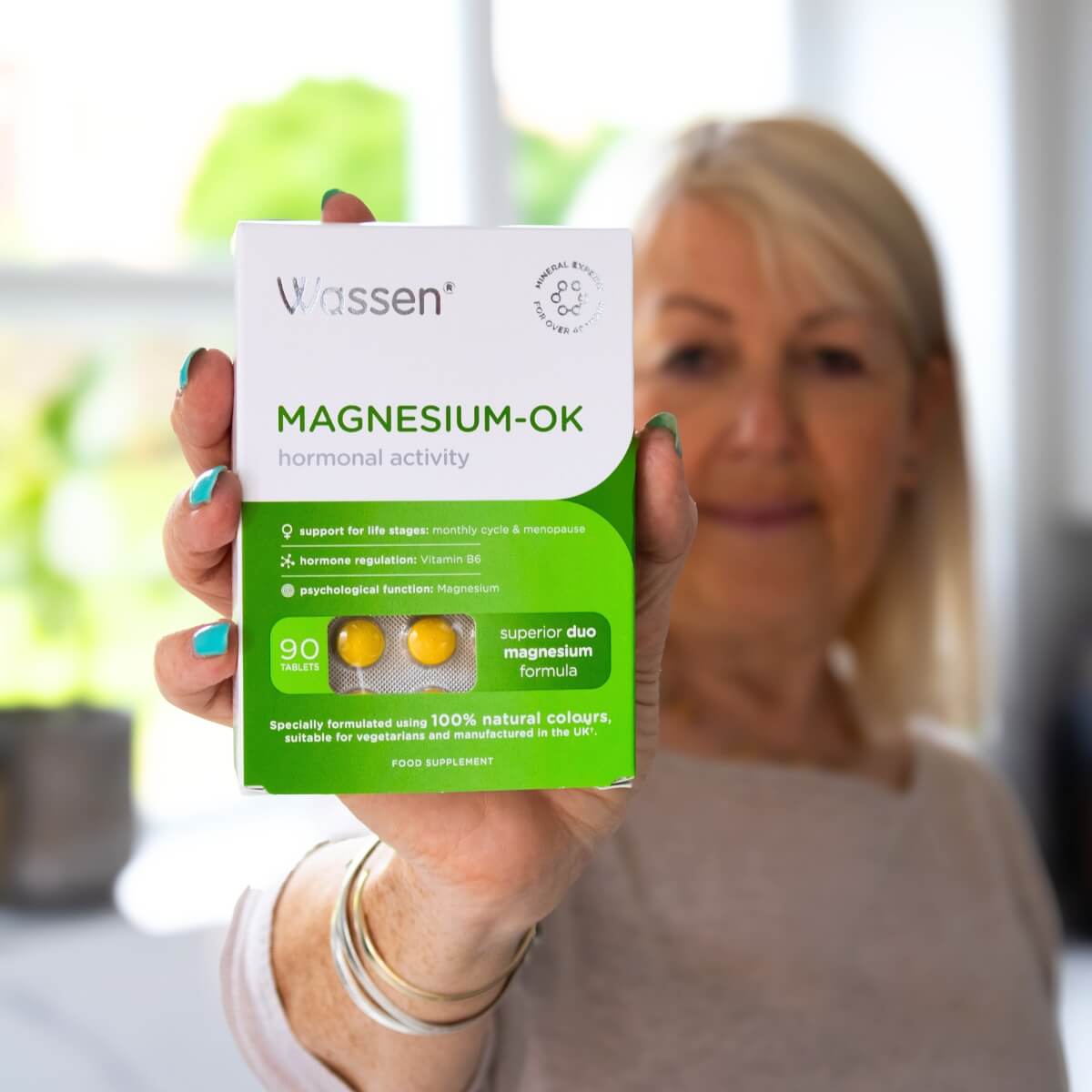 Magnesium-OK customer holding a pack of the supplement, smiling